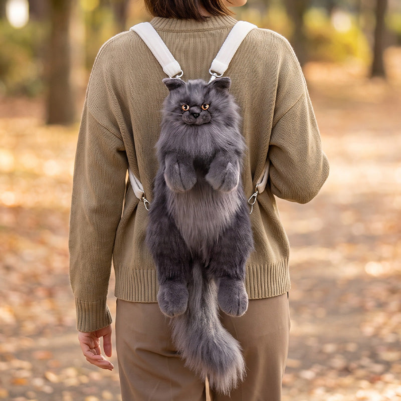 Lifelike Maine Coon cat plush backpack in black, worn over a beige sweater on an autumn walk