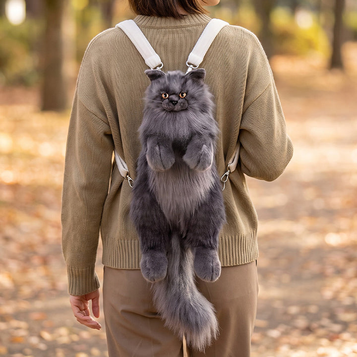 Lifelike Maine Coon cat plush backpack in black, worn over a beige sweater on an autumn walk