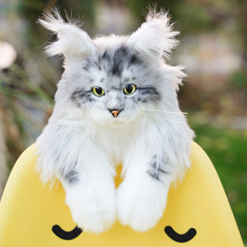 Lifelike Maine Coon cat plush backpack in gray, close-up of the face sitting on a yellow chair