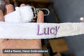 White plush backpack strap with a hand-embroidered name in purple thread - Chobyner workshop